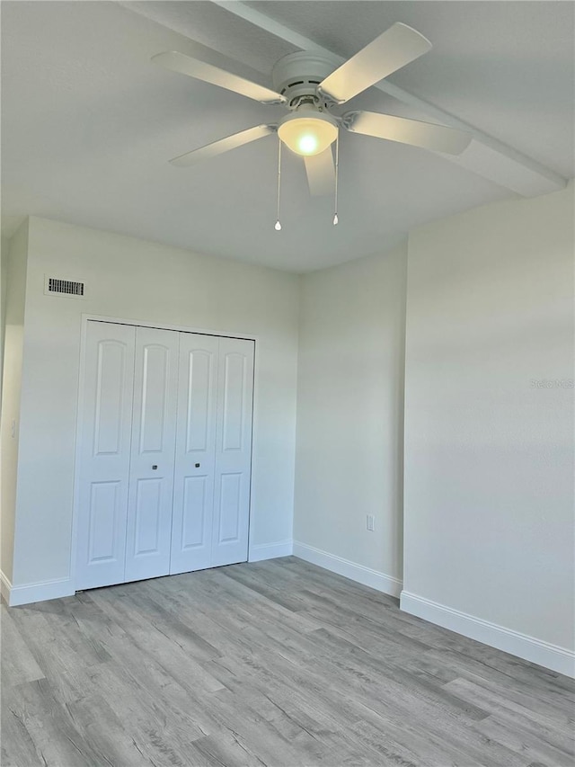 unfurnished bedroom featuring light hardwood / wood-style floors, a closet, and ceiling fan