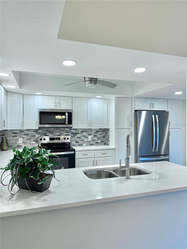 kitchen with appliances with stainless steel finishes, decorative backsplash, white cabinets, and sink