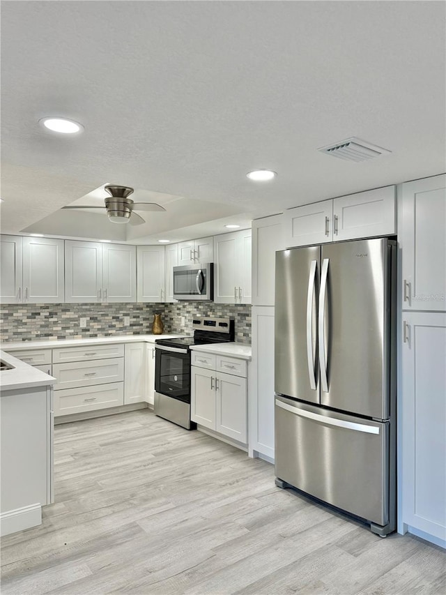 kitchen with white cabinetry, stainless steel appliances, and light wood-type flooring