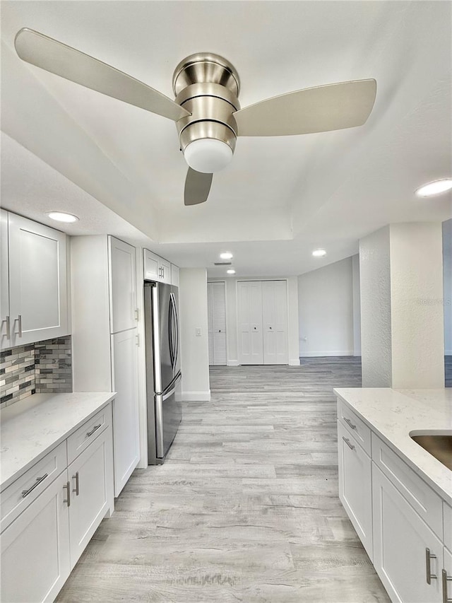 kitchen featuring stainless steel fridge, white cabinetry, and light wood-type flooring