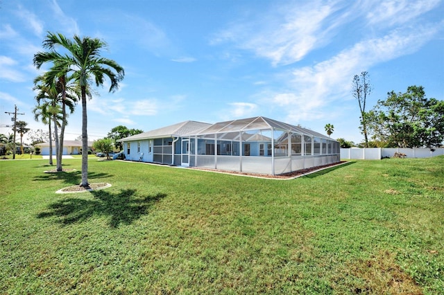 rear view of house featuring a lanai and a lawn