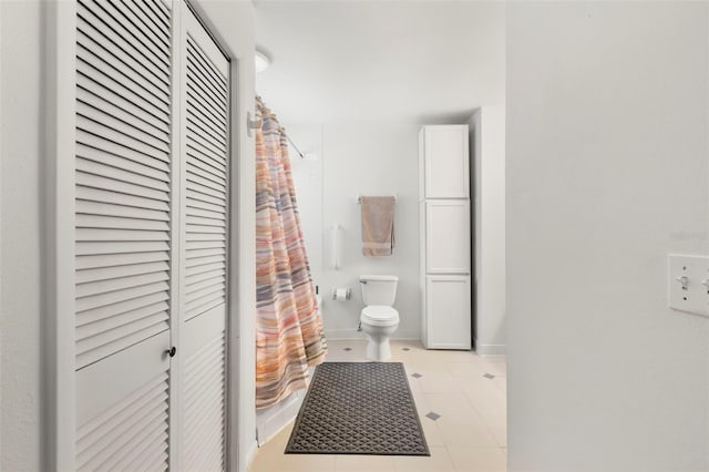 bathroom featuring toilet, curtained shower, and tile patterned flooring