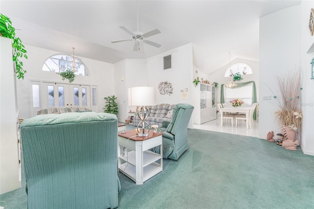 carpeted living room with ceiling fan with notable chandelier and high vaulted ceiling