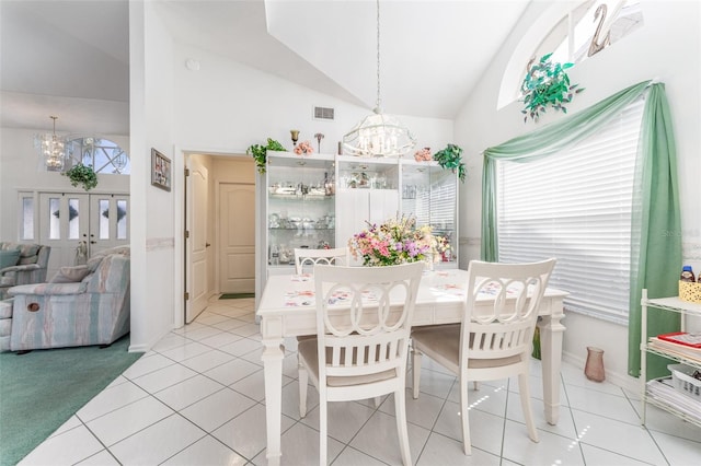 tiled dining space featuring a notable chandelier and high vaulted ceiling