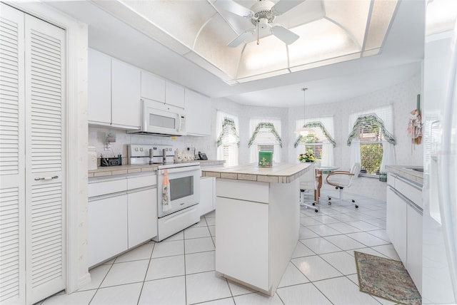 kitchen with white appliances, tile countertops, light tile patterned floors, and white cabinets