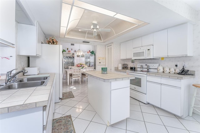 kitchen featuring ceiling fan, a raised ceiling, white cabinetry, sink, and white appliances