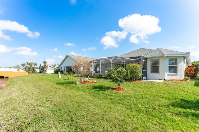 rear view of property with a yard and glass enclosure