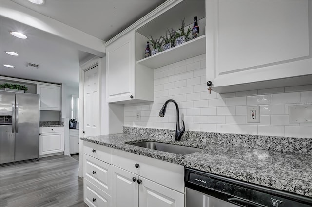 kitchen featuring stainless steel appliances, stone countertops, white cabinetry, and sink