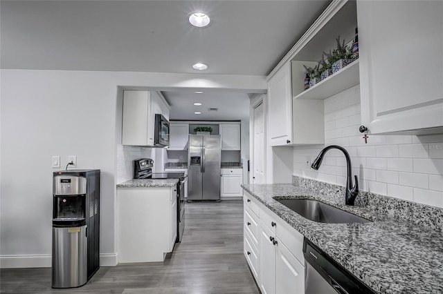 kitchen featuring light stone counters, stainless steel appliances, white cabinetry, dark hardwood / wood-style flooring, and sink