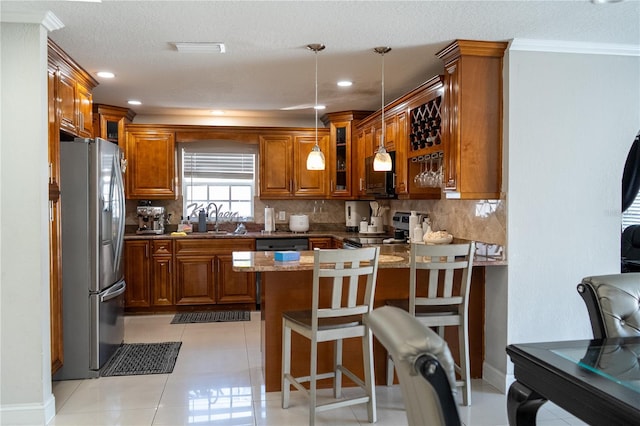 kitchen featuring sink, kitchen peninsula, hanging light fixtures, stainless steel appliances, and dark stone countertops