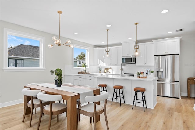 dining room with light wood-type flooring, sink, and a chandelier