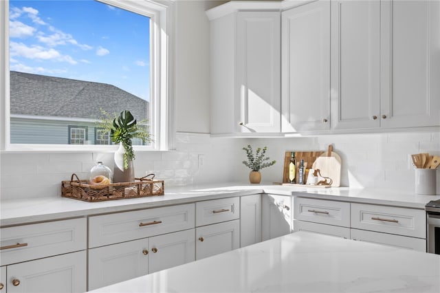 kitchen featuring decorative backsplash, white cabinetry, and a healthy amount of sunlight