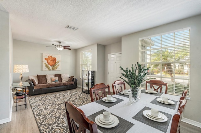 dining area with hardwood / wood-style floors, a textured ceiling, and ceiling fan