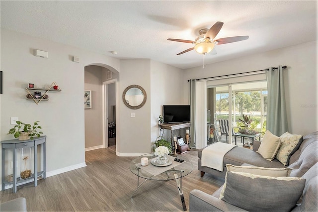 living room with a textured ceiling, wood-type flooring, and ceiling fan