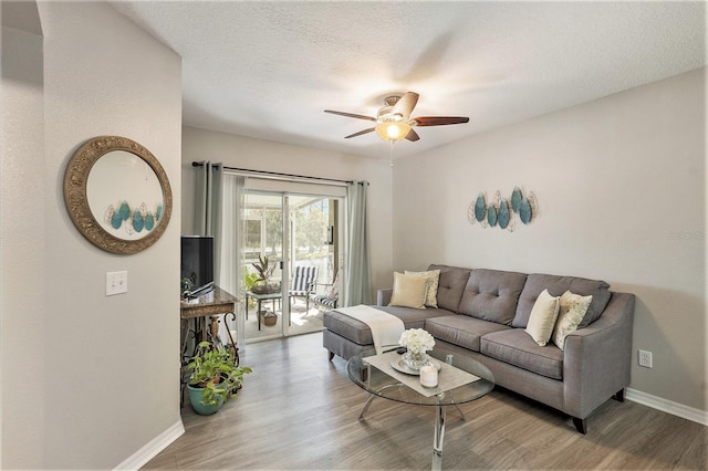 living room with a textured ceiling, light wood-type flooring, and ceiling fan