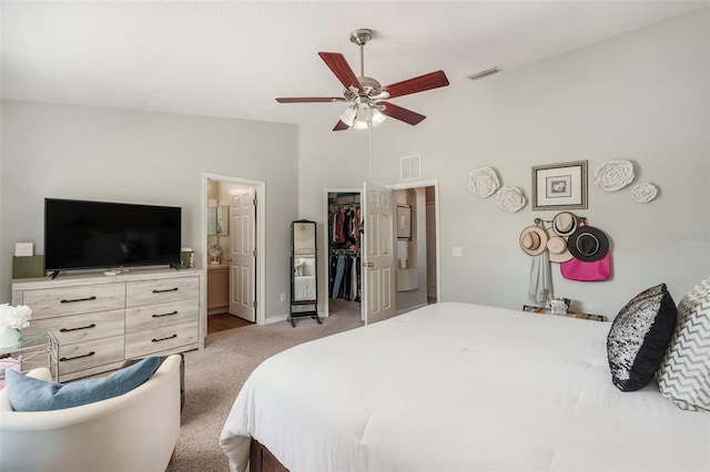 bedroom with a closet, a spacious closet, vaulted ceiling, light colored carpet, and ensuite bathroom