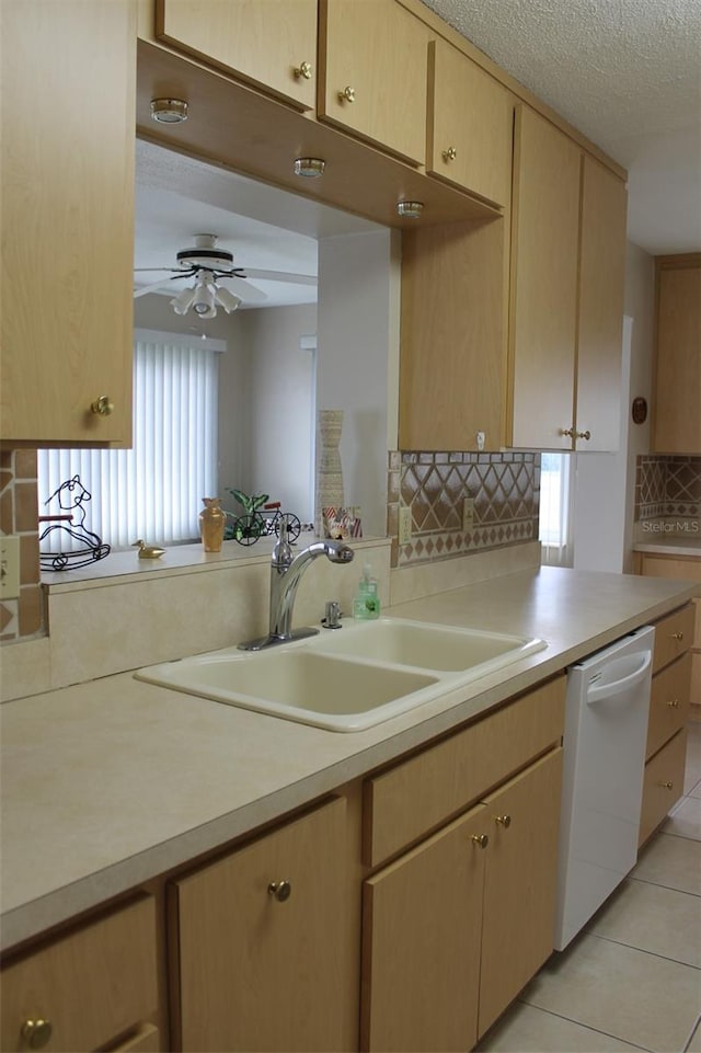 kitchen with tasteful backsplash, light tile patterned floors, a textured ceiling, dishwasher, and sink