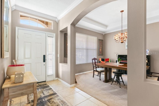 carpeted foyer entrance featuring crown molding and a chandelier