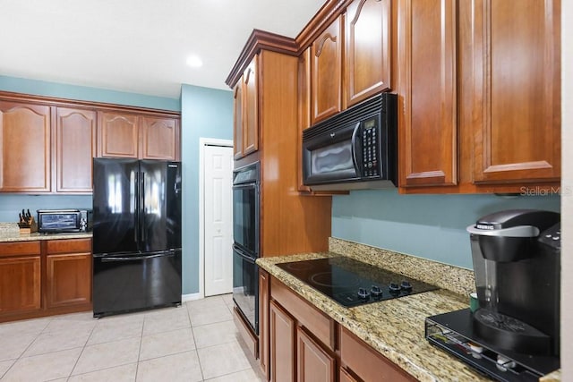 kitchen with light stone countertops, black appliances, and light tile patterned floors