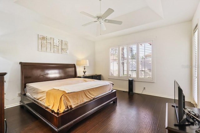 bedroom featuring a raised ceiling, dark hardwood / wood-style floors, and ceiling fan