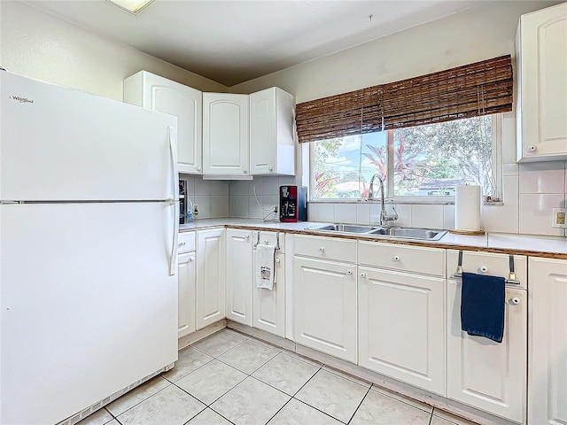 kitchen with backsplash, sink, light tile patterned flooring, white refrigerator, and white cabinets