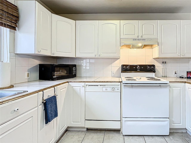 kitchen with white appliances, sink, light tile patterned flooring, white cabinetry, and decorative backsplash