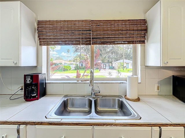 kitchen with white cabinetry, tasteful backsplash, and sink