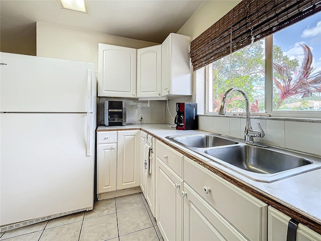 kitchen featuring decorative backsplash, sink, light tile patterned flooring, white cabinetry, and white fridge