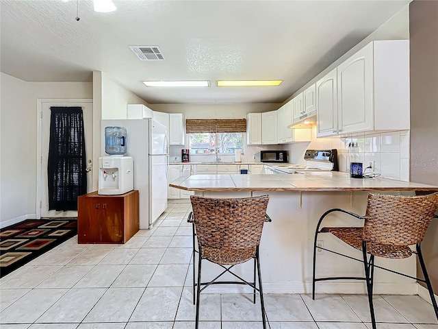 kitchen featuring white cabinets, black appliances, kitchen peninsula, and a kitchen breakfast bar