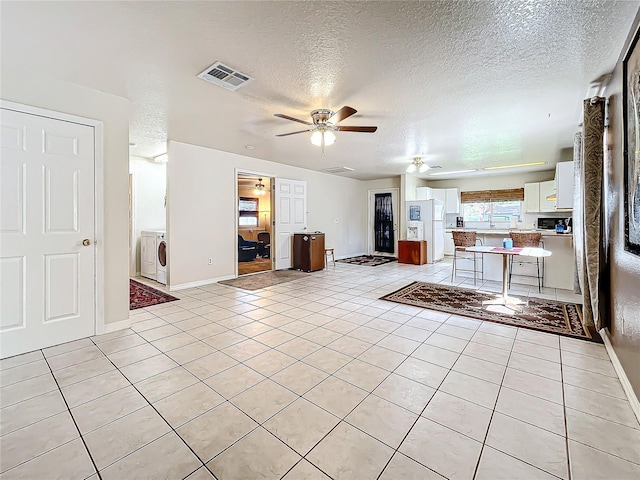 unfurnished living room with ceiling fan, a textured ceiling, and light tile patterned floors