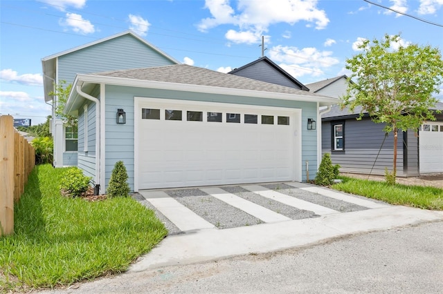 exterior space featuring fence, a shingled roof, and a garage