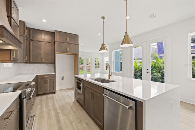 kitchen with visible vents, custom range hood, a sink, stainless steel appliances, and light wood-style flooring