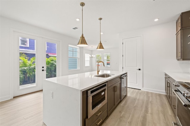 kitchen with light wood-style floors, a sink, light countertops, and stainless steel appliances
