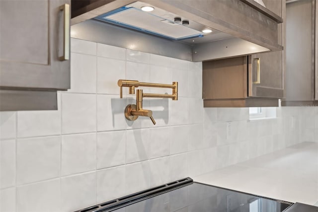 room details featuring light countertops, wall chimney exhaust hood, and tasteful backsplash