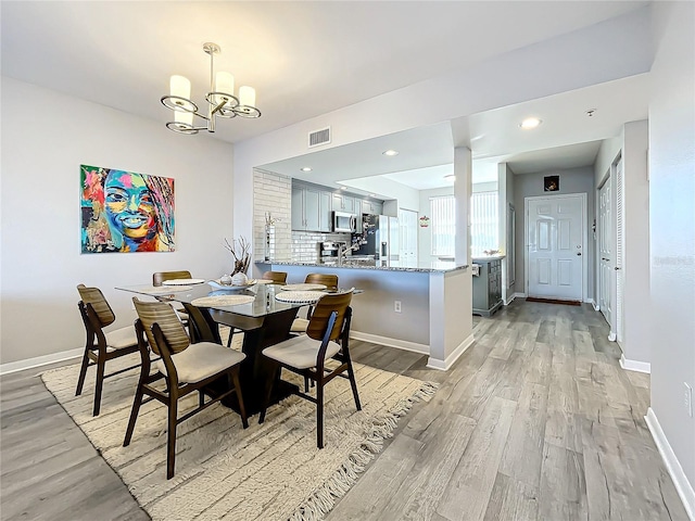 dining space featuring light hardwood / wood-style floors and a chandelier