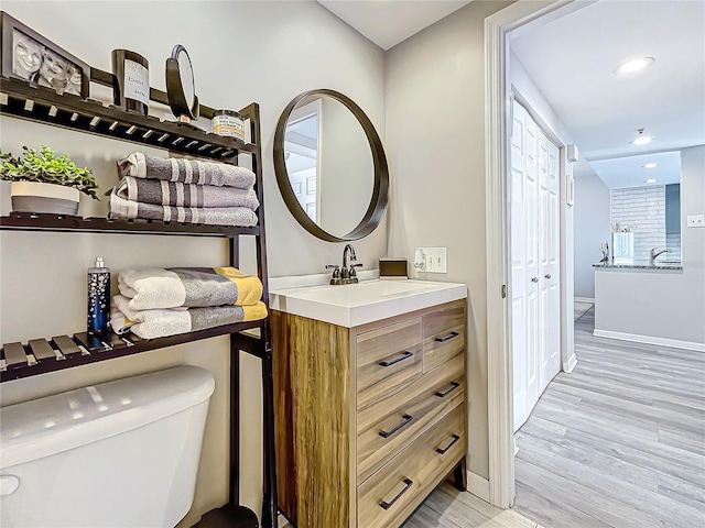 bathroom with toilet, vanity, and wood-type flooring