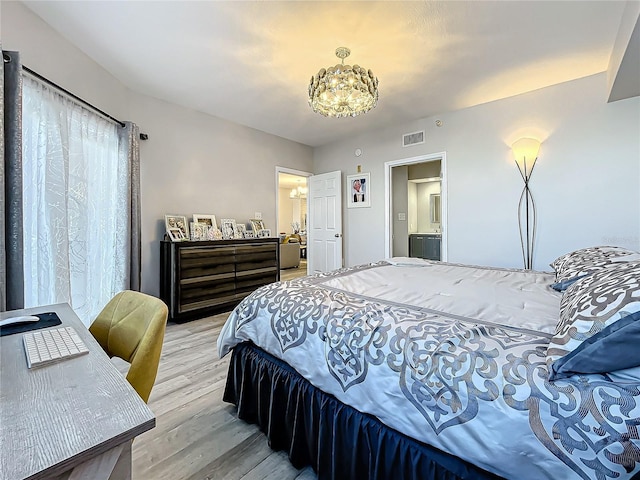 bedroom featuring light hardwood / wood-style flooring, ensuite bath, and a notable chandelier