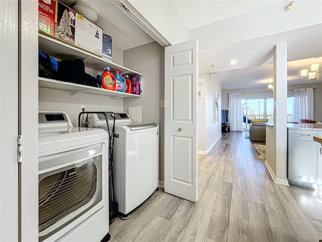 laundry room featuring an inviting chandelier, separate washer and dryer, and light hardwood / wood-style floors