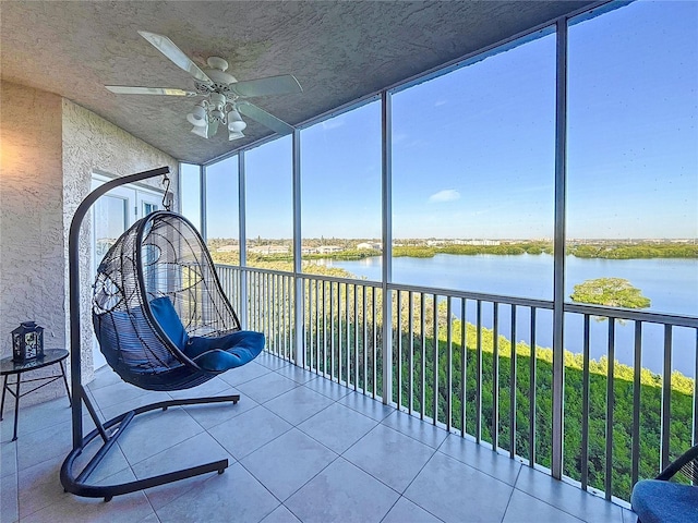 unfurnished sunroom featuring a water view and ceiling fan