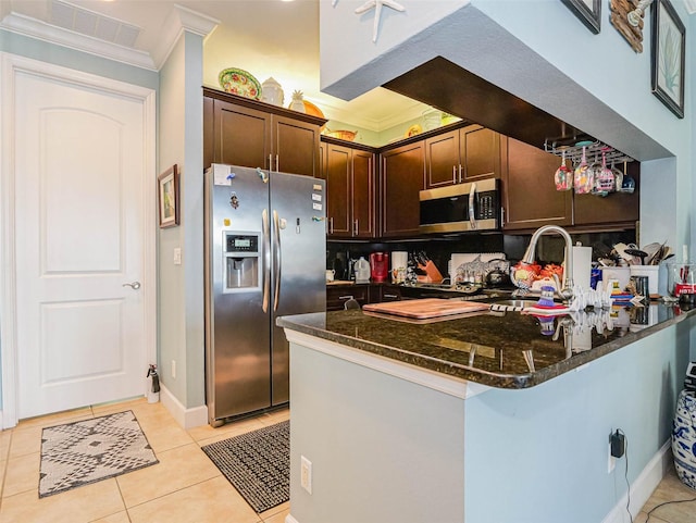 kitchen with kitchen peninsula, light tile patterned floors, appliances with stainless steel finishes, crown molding, and dark brown cabinetry