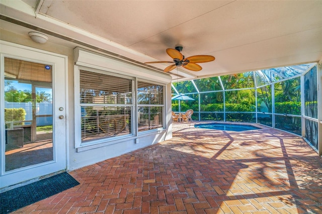 view of swimming pool featuring ceiling fan, glass enclosure, and a patio