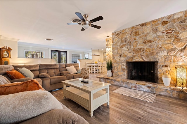 living room with a wealth of natural light, wood-type flooring, a fireplace, ceiling fan, and crown molding