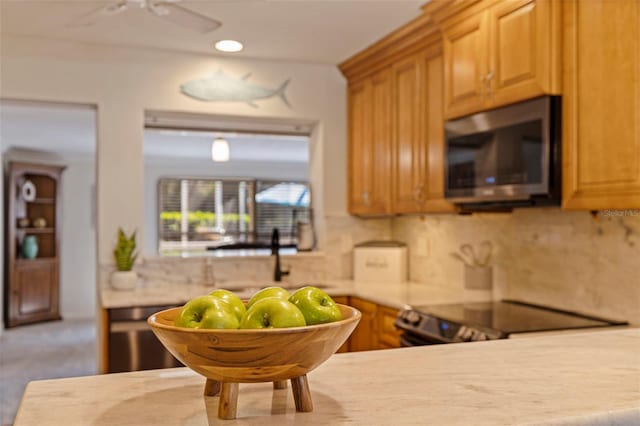 kitchen with decorative backsplash, sink, ceiling fan, and stove