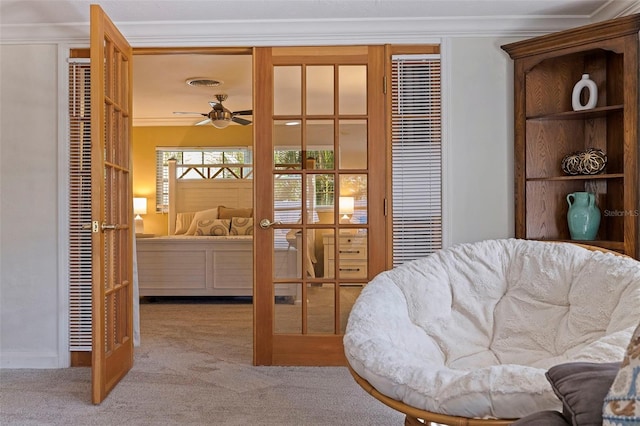 living area featuring ceiling fan, carpet, ornamental molding, and french doors