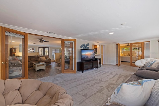 carpeted living room with ceiling fan, plenty of natural light, ornamental molding, and french doors