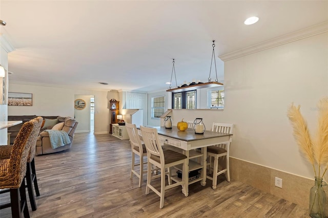 dining space featuring wood-type flooring and crown molding