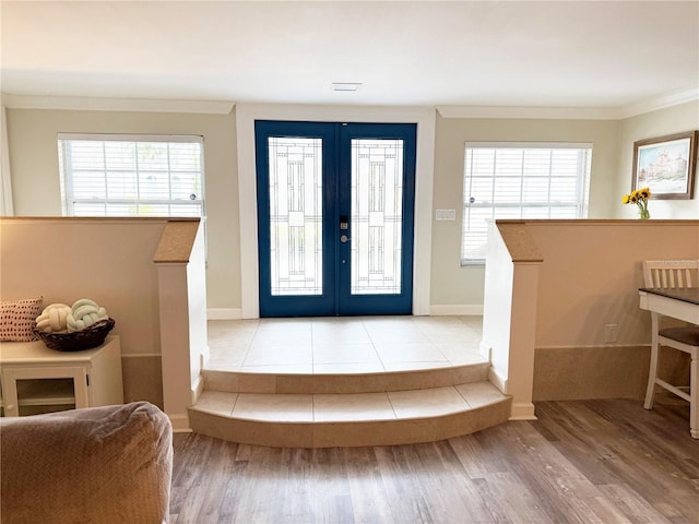 entryway with light wood-style floors, french doors, crown molding, and baseboards