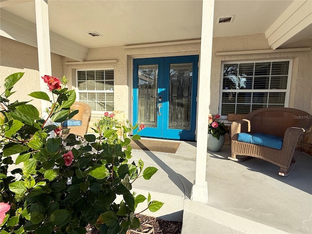 doorway to property with french doors, visible vents, and stucco siding