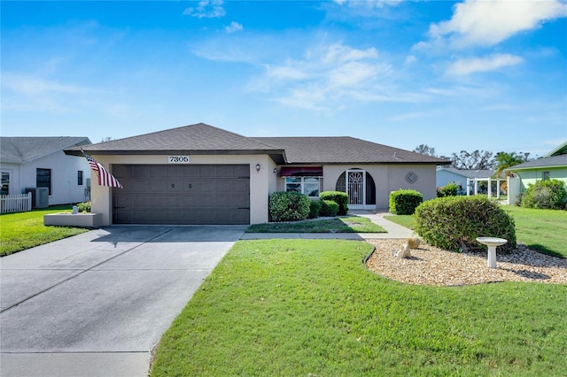 single story home featuring cooling unit, a front yard, and a garage