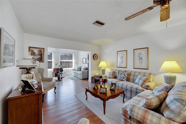 living room with a textured ceiling, light hardwood / wood-style floors, and ceiling fan